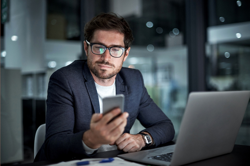 Shot of a young businessman using his laptop and phone at work